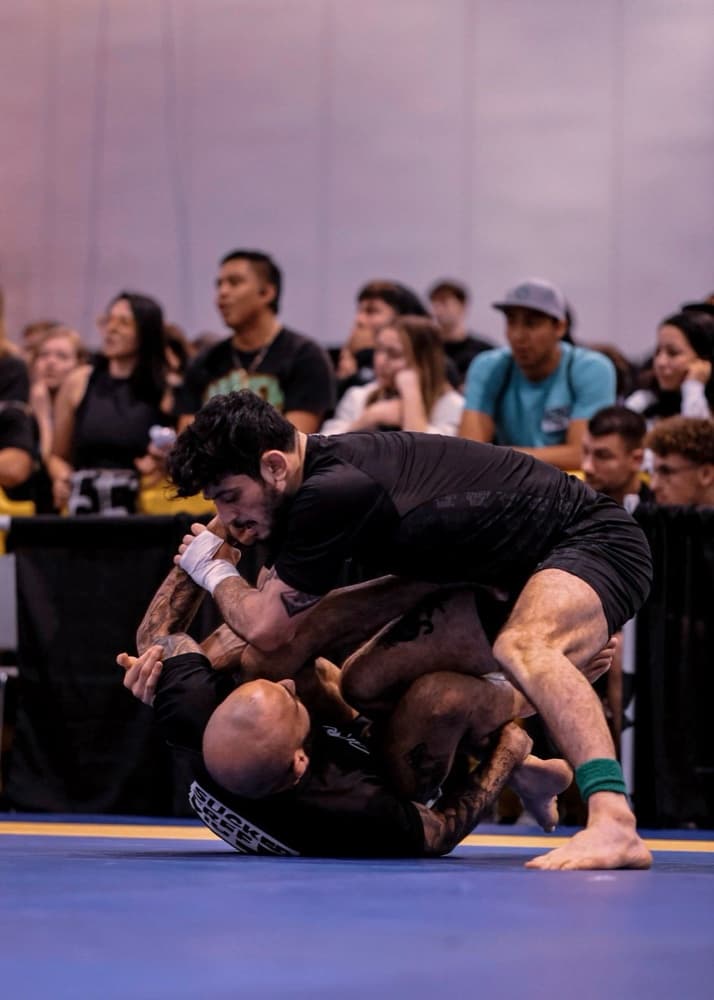 A Black Cat grappler working from top position during a competition match.